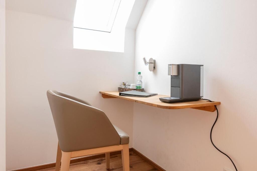 Een hoekkamer met een bureau, stoel en een klein raam.
