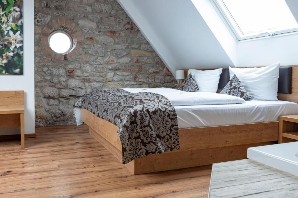 A loft bedroom with a sloped ceiling, exposed stone wall, and a skylight.