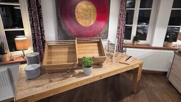 Una mesa de madera con bandejas, una planta en maceta y una lámpara en una habitación con cortinas estampadas y un cuadro circular grande en la pared.