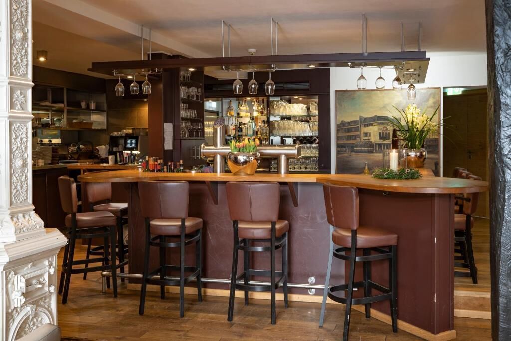 A bar area with a counter, bar stools, and a display of bottles and glasses.