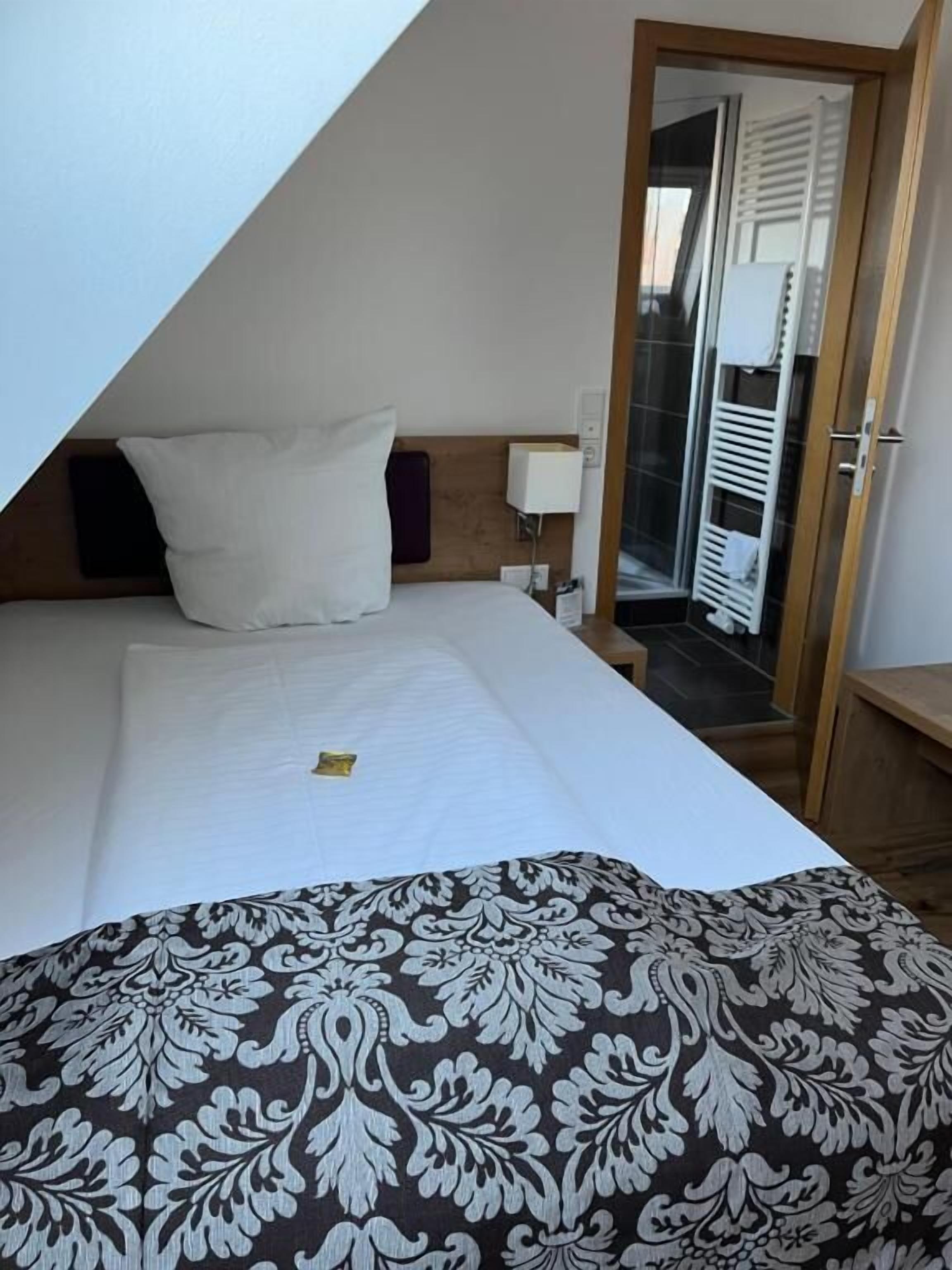 A hotel room with a bed, a nightstand, a lamp, and a view of a balcony.