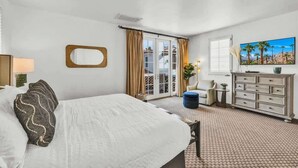 Une chambre d’hôtel avec un grand lit, une commode, une télévision et une vue sur l’extérieur.