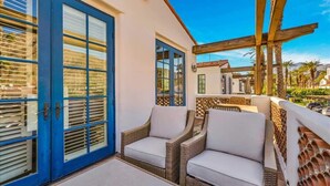 Un balcon avec des meubles en osier et une porte bleue.
