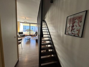 Staircase leads to a cozy upper level with a balcony and seating area below.
