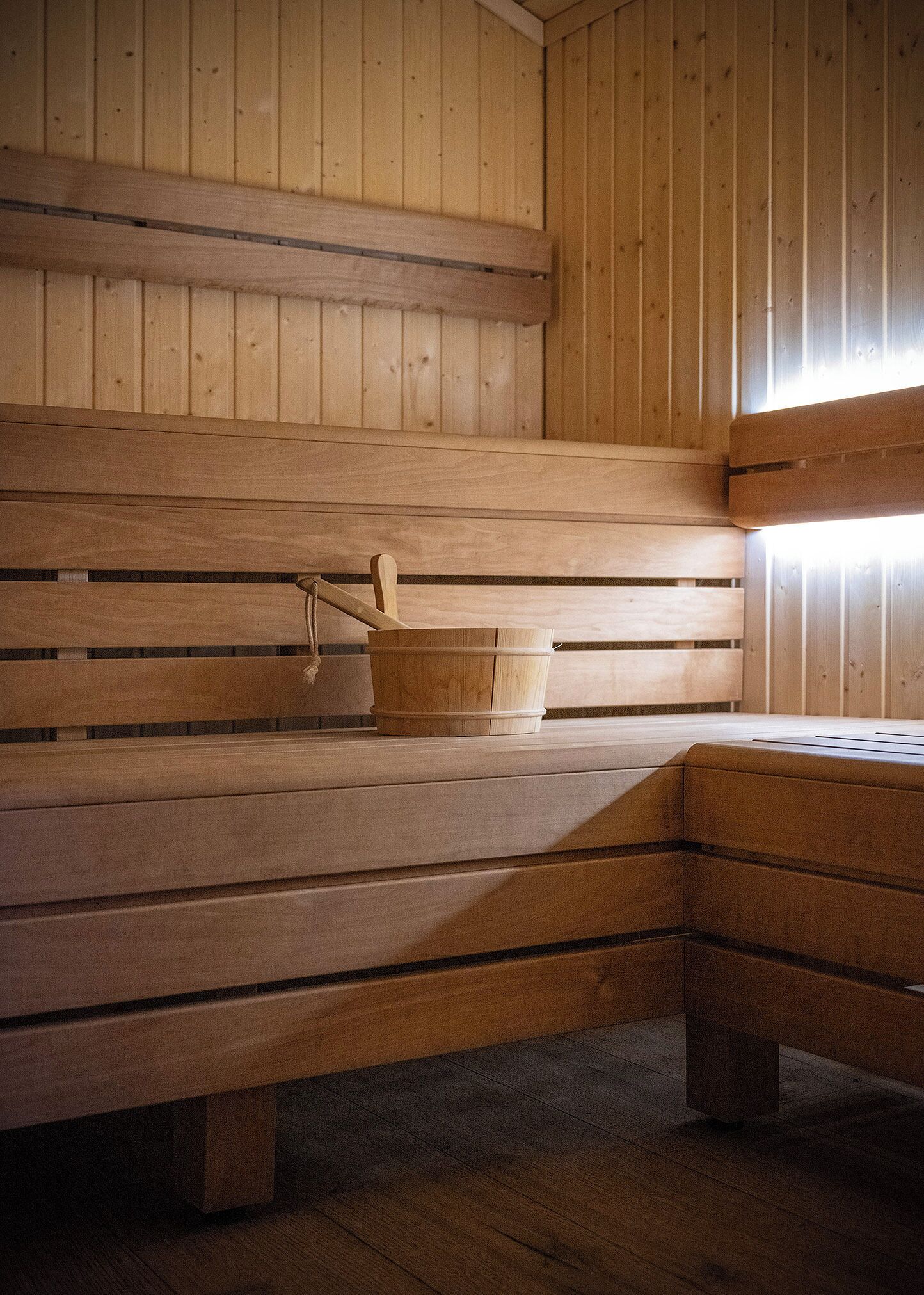 Un sauna en bois avec des bancs et un seau en bois.