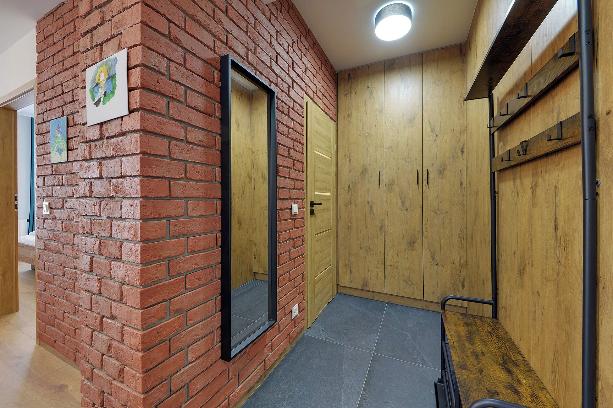 Un pasillo con pared de ladrillo, puerta y armario de madera.