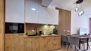 Eine moderne Küche mit Holzausstattung, einer schwarzen Mikrowelle und einer Kaffeemaschine.