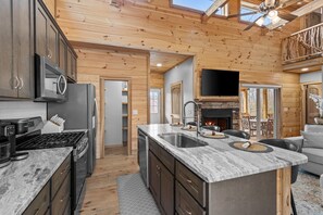 Una cocina moderna con encimeras de granito, electrodomésticos de acero inoxidable y una chimenea de piedra.