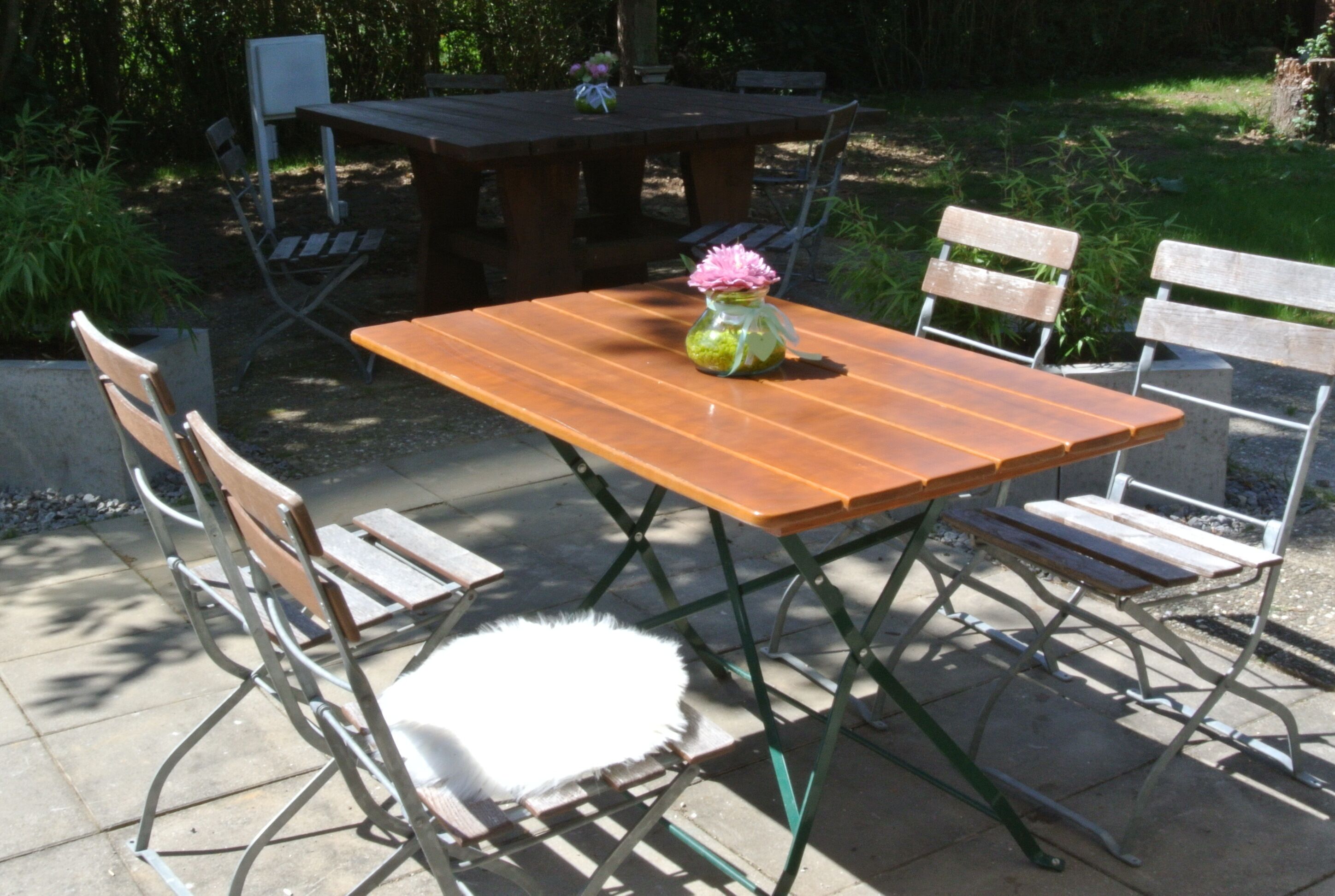 An outdoor patio with a wooden table and metal chairs.