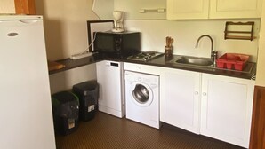Cocina compacta con refrigerador, microondas, lavamanos y lavadora.