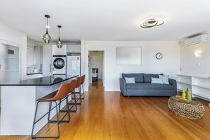 A modern apartment with a kitchen, dining area, and living room. - Renovated Home with Lovely Garden by Zodiak Stay (Auckland)