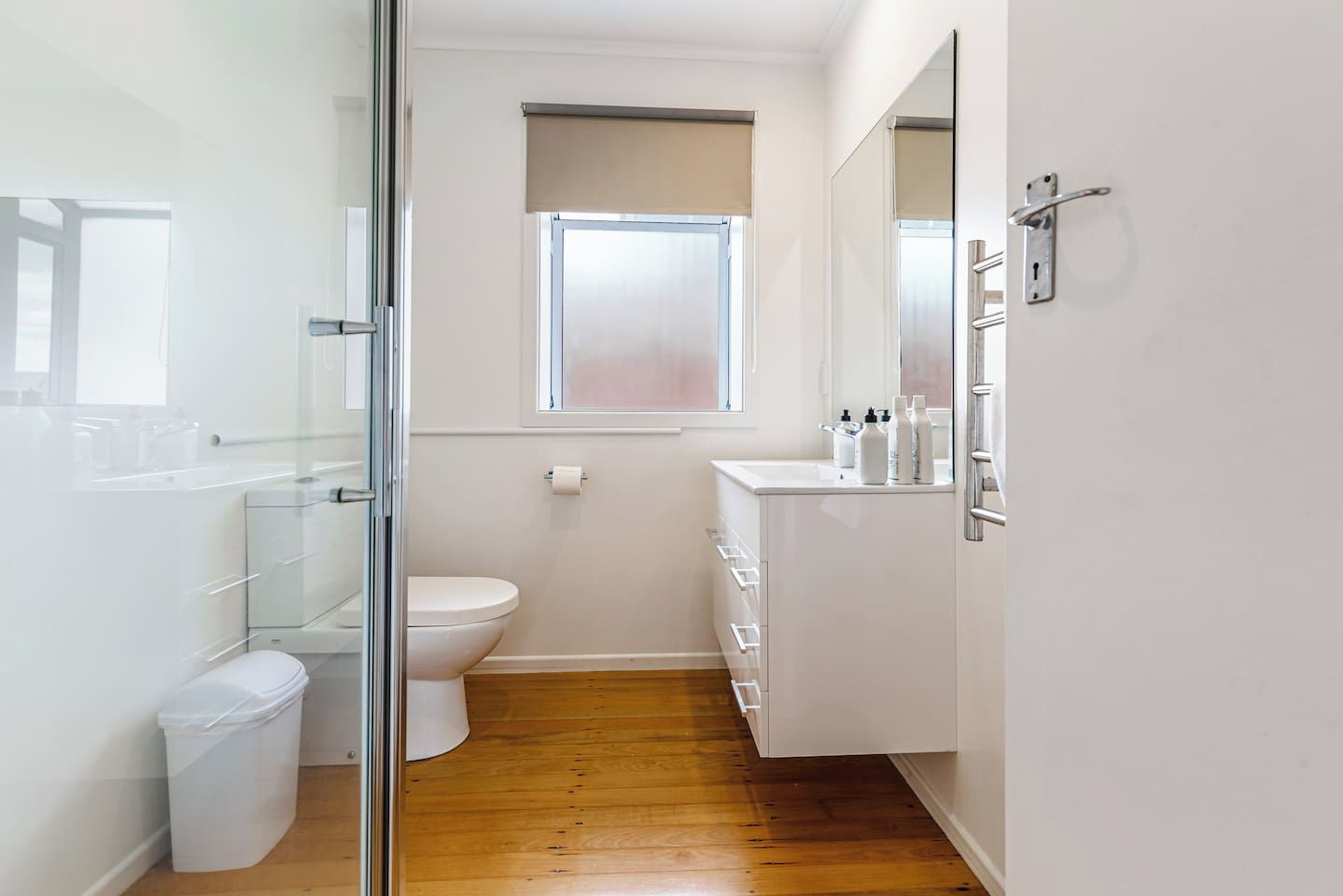 Et lille, moderne badeværelse med toilet, vask og et vindue.