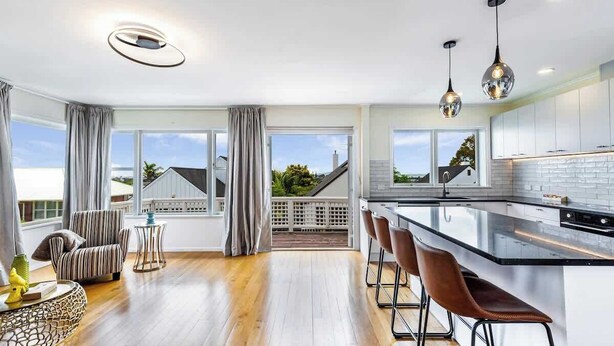 Una cocina moderna con una isla grande, taburetes de bar e iluminación colgante.