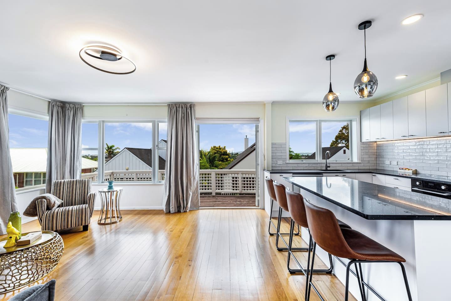 Een moderne keuken met een groot eiland, barkrukken en hanglampen.