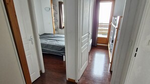 A narrow hallway with a bed and a window.