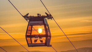 A cable car suspended above a desert landscape during sunset.