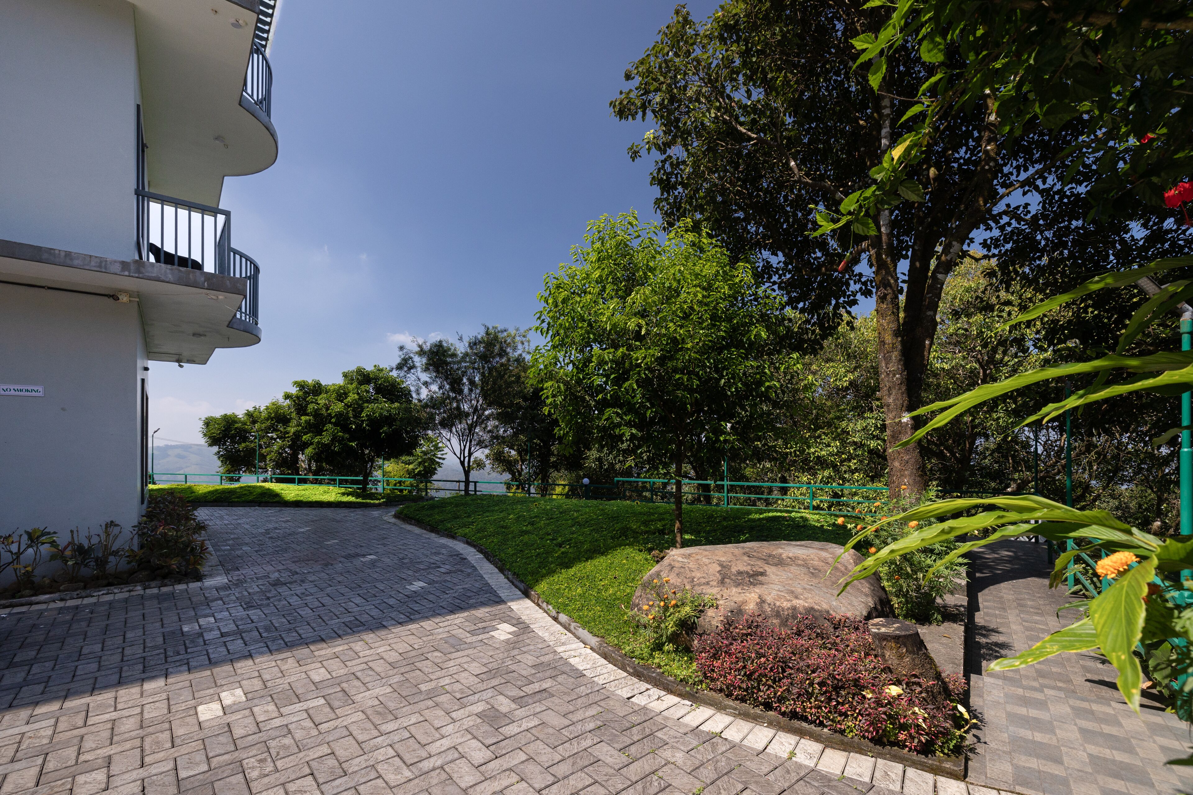 A paved pathway leading to a building with a balcony.