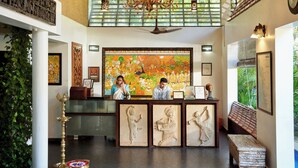 A reception area with a large mural, a chandelier, and a wooden bench. - Anandalakshmi Ayurveda Retreat (Neyyattinkara)