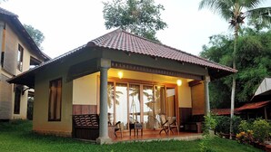 A small, single-story house with a tiled roof, large windows, and a porch with chairs. - Anandalakshmi Ayurveda Retreat (Neyyattinkara)
