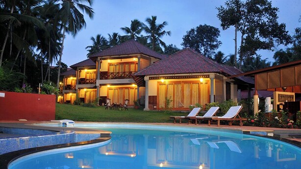 A two-story resort with a swimming pool, lounge chairs, and a well-maintained garden. - Anandalakshmi Ayurveda Retreat (Neyyattinkara)