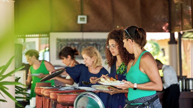 A group of people at a buffet with various dishes and serving utensils. - Anandalakshmi Ayurveda Retreat (Neyyattinkara)