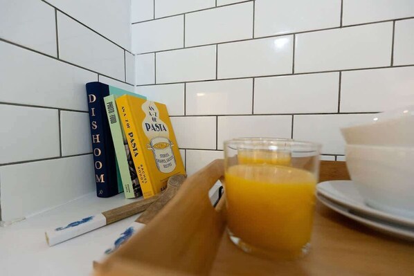 A kitchen counter with a tray holding a glass of orange juice, a bowl, and a book titled "DI SHOM".