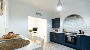 Una cocina moderna con armarios azul oscuro, encimera blanca y salpicadero de azulejos.