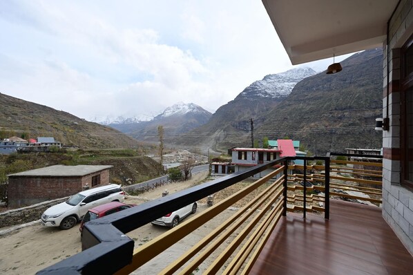 A balcony with a view of a mountainous landscape, a paved road, and a few buildings.