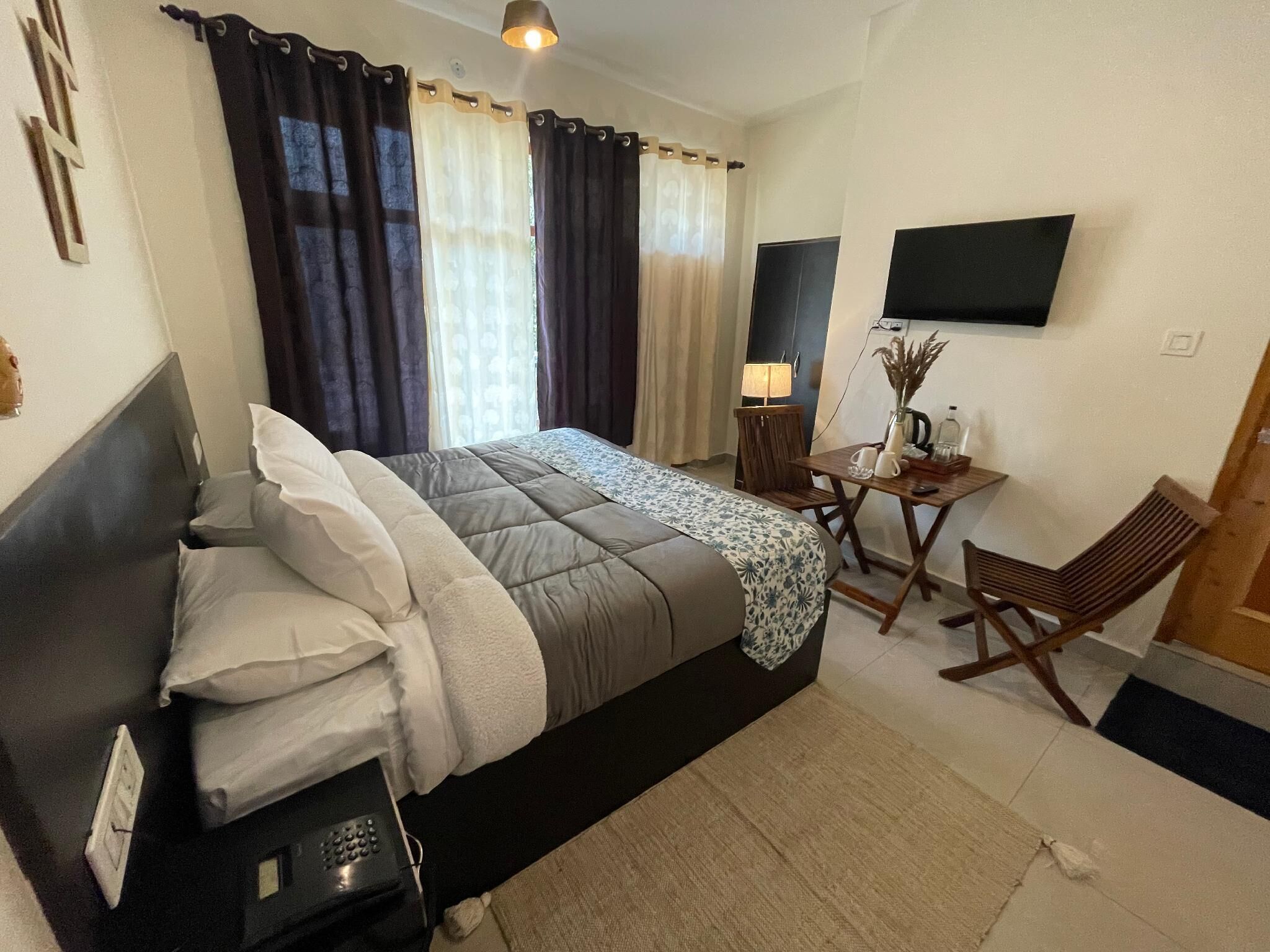 A hotel room with a bed, a desk, a chair, a TV, and curtains.