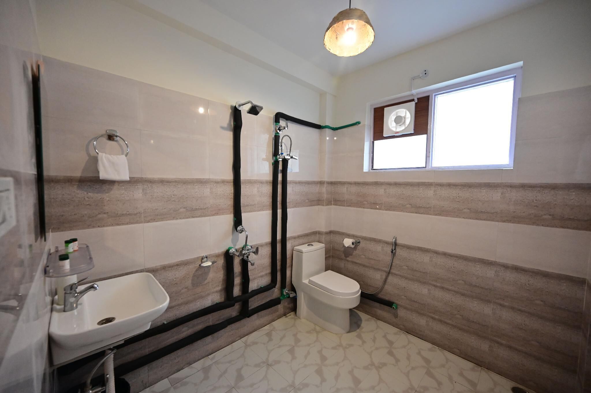 A bathroom with a sink, toilet, shower, and a window.