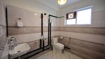 A bathroom with a sink, toilet, shower, and a window.