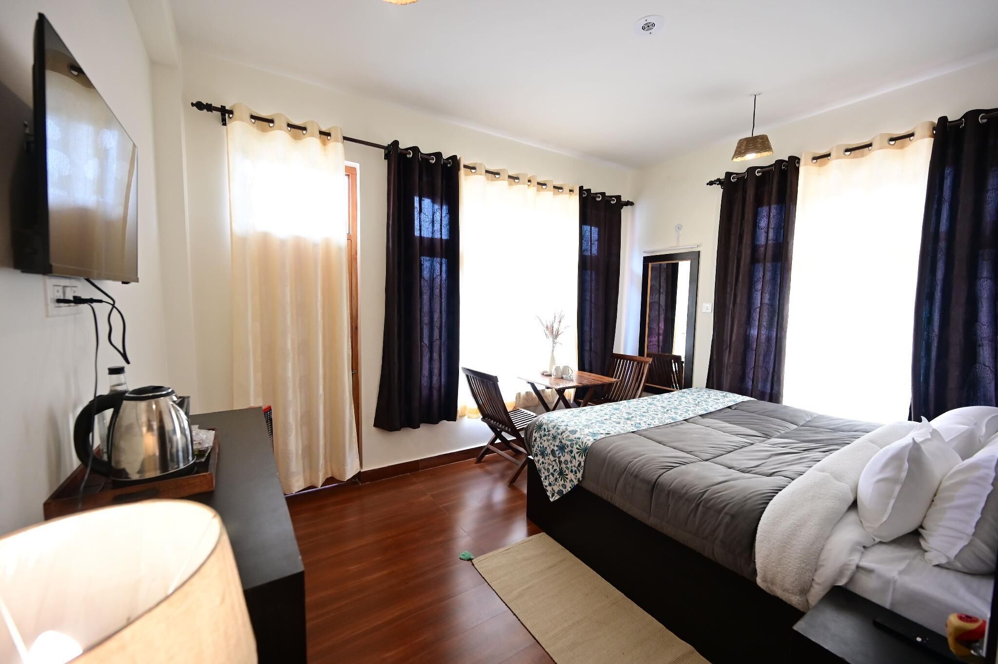 A hotel room with a bed, a desk, a chair, a TV, and curtains.