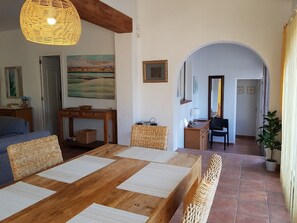 A cozy living room with a wooden dining table, wicker furniture, and a large painting on the wall. - VILLA MIKAELA, PETS ALLOWED (VC)