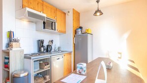 A compact kitchen with wooden cabinets, a microwave, a refrigerator, and a wooden countertop.