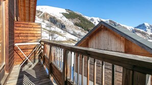 A wooden cabin with a balcony overlooking a snowy mountain landscape.