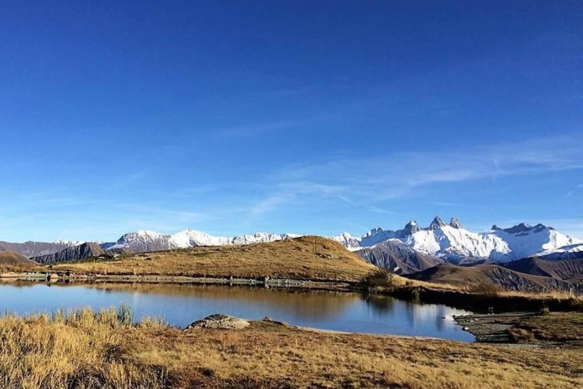 A mountainous landscape with a lake and snow-capped peaks.