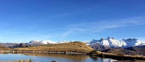 A mountainous landscape with a lake and snow-capped peaks.