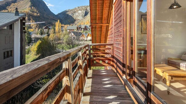 Un balcon en bois offrant une vue sur une montagne et une ville.