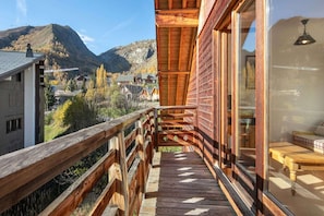 A wooden balcony with a view of a mountain and a town.