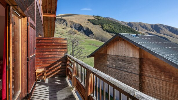 A wooden cabin with a balcony overlooking a mountainous landscape.