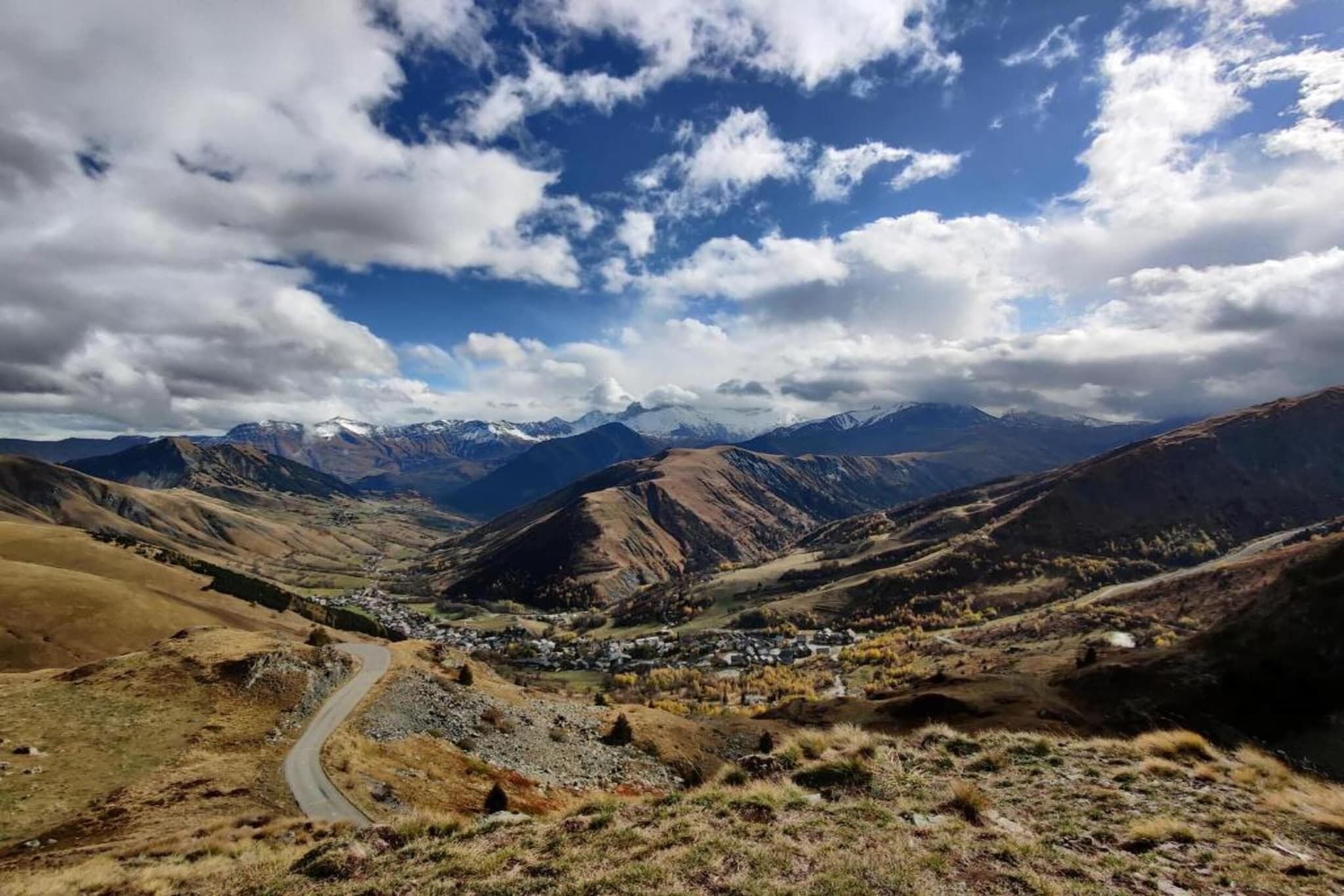 Un paysage montagneux, avec une route sinueuse qui mène à un petit village.