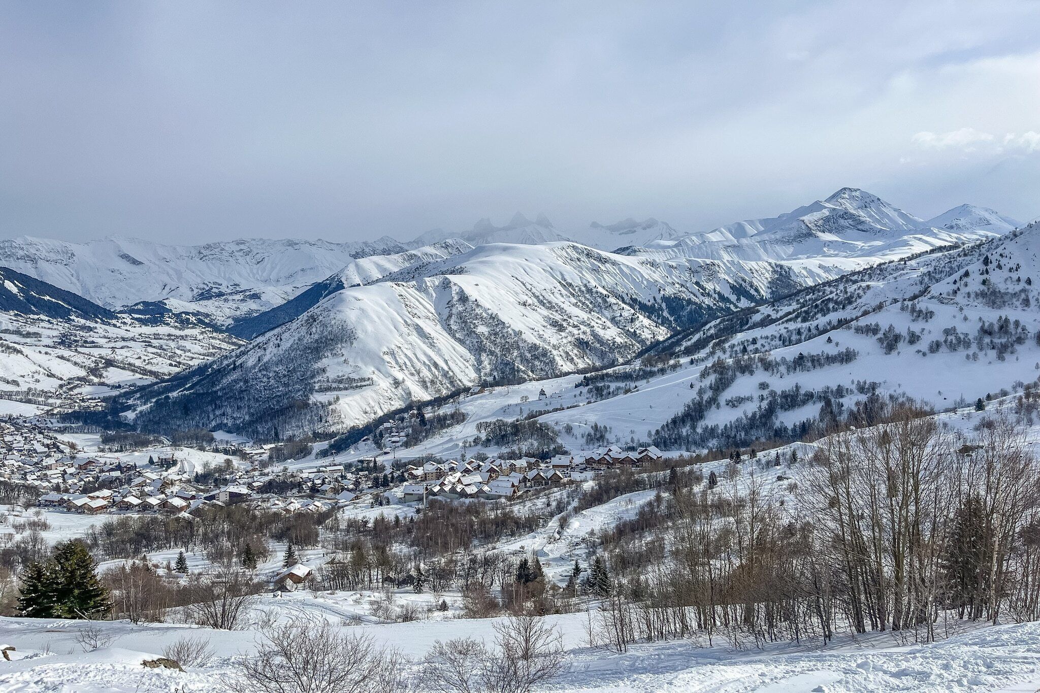 Un paysage montagneux enneigé, avec une ville nichée au fond de la vallée.
