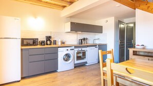 A compact kitchen with a washing machine, oven, and microwave.