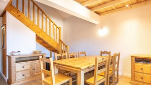 A wooden dining table with chairs, a wooden staircase, and a wooden cabinet.