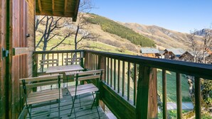 A wooden balcony with benches overlooking a mountainous landscape.