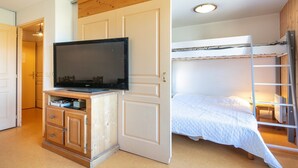 Ein Schlafzimmer mit einem Etagenbett, einem Fernseher auf einer Holzkommode und einer Tür zu einem weiteren Raum.