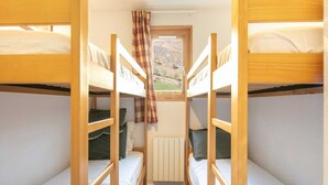 Een slaapzaal met stapelbedden, een raam met uitzicht op de omgeving en een radiator.