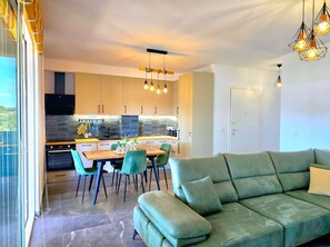 Una cocina moderna con comedor, un sofá verde y vistas al exterior.