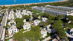 A coastal residential area with modern houses, a large building with solar panels, and a beach with sailboats.