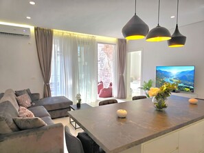 Een moderne woonkamer met een bank, een eettafel en een televisie waarop een mooi uitzicht te zien is.